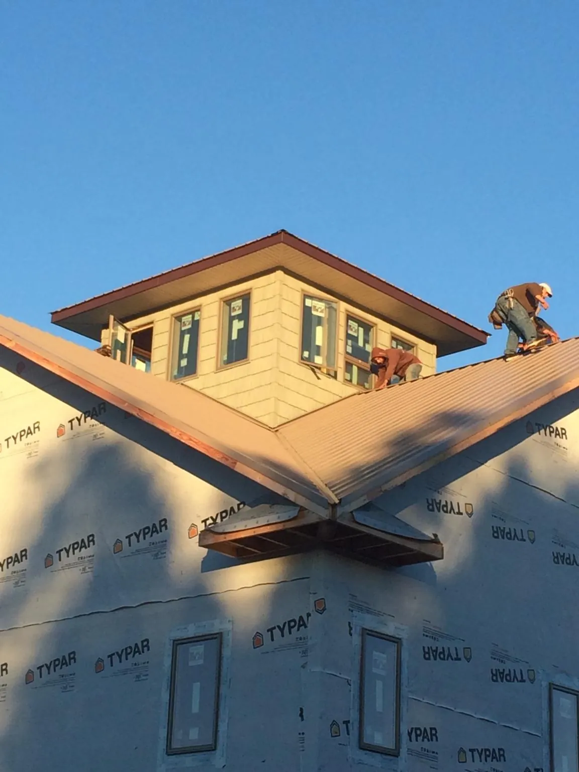 Roofers working around a rooftop cupola on a new metal roof at sunset — Roof Waterproofing in Viola by Roofing Brothers